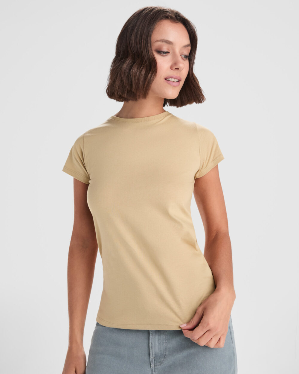 Mujer con camiseta beige sobre fondo neutro
