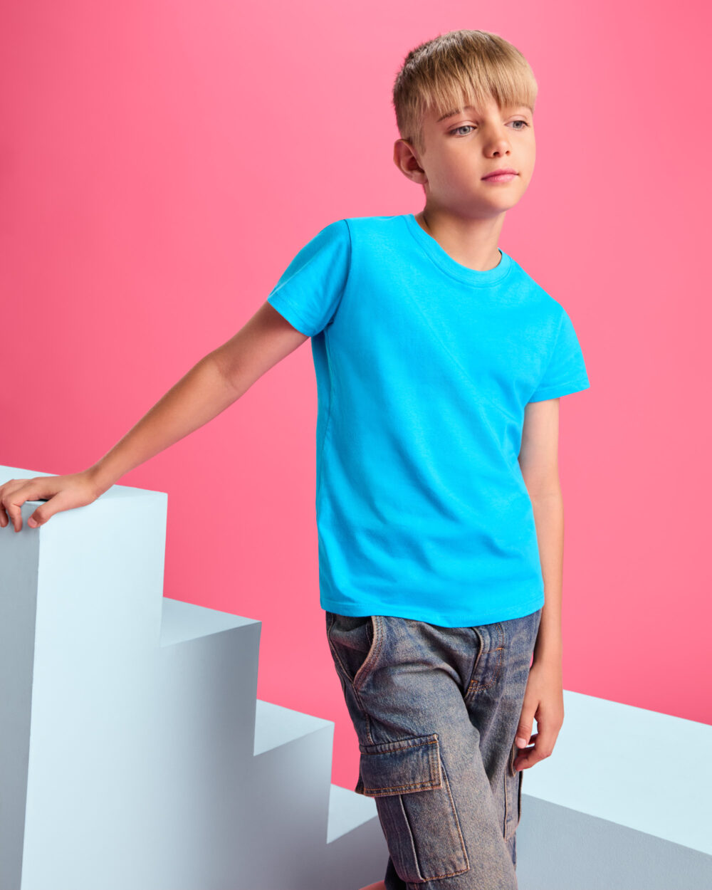 Niño con camiseta azul sobre fondo rosa