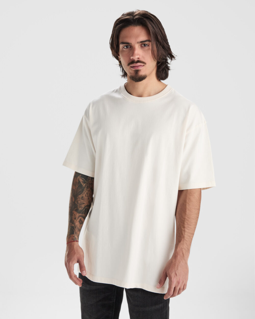 Hombre con camiseta beige y tatuaje en brazo