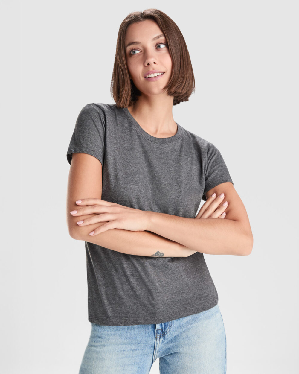 Mujer joven con camiseta gris y brazos cruzados
